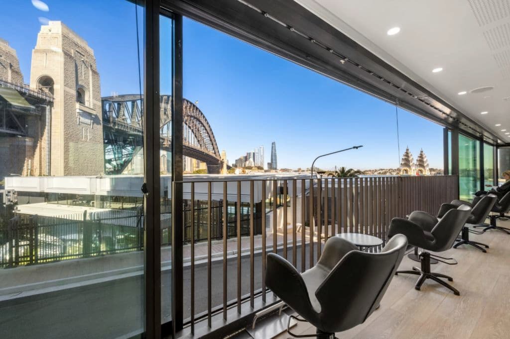 A chair looking out to the Sydney Harbour Bridge with open windows.