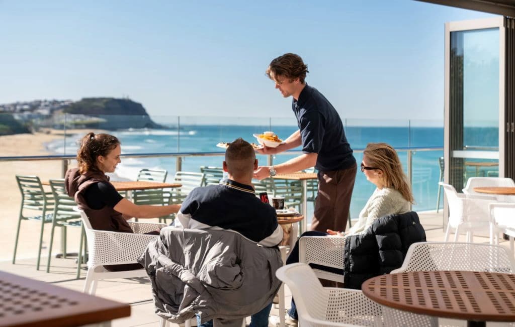 Diners sit at a table while a staff member serves their table.