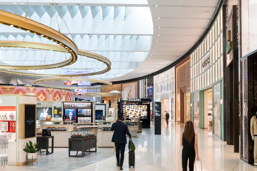 People wheel suitcases through Sydney Airport luxury zone
