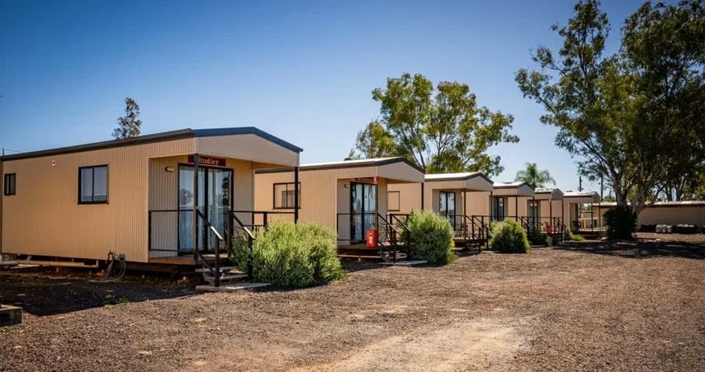 Four modern cabins with balconies lined up on the site.