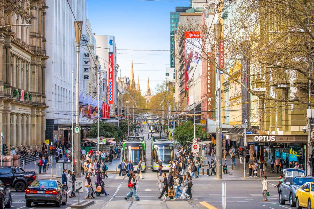 Pedestrians and trams along Bourke Street Mall, lined with Myer and David Jones.