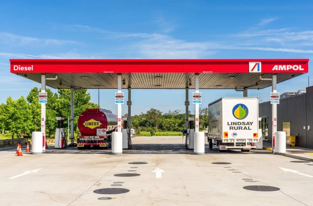 Two large trucks fill up their tanks under a canopy.