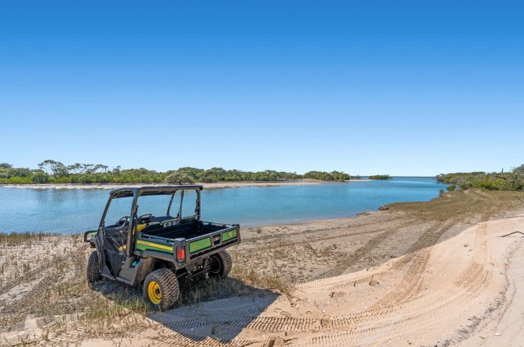 A John Deere ride on mower vehicle sits by the water.