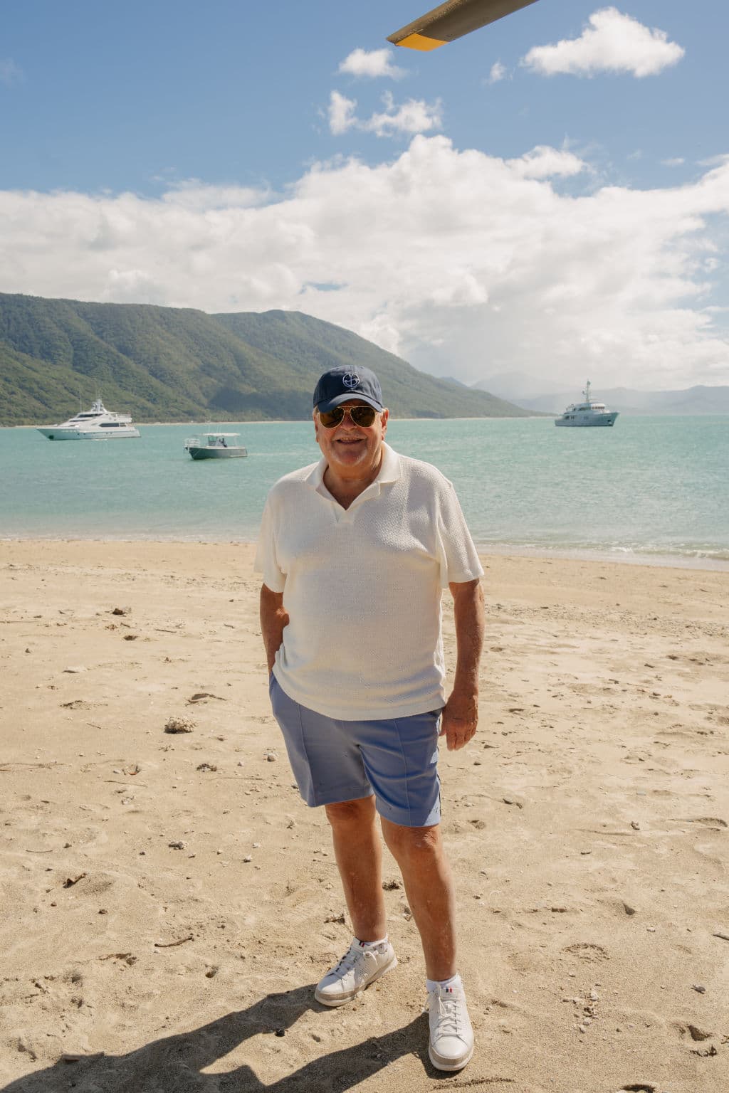 A man stands on sand with an island in the background.