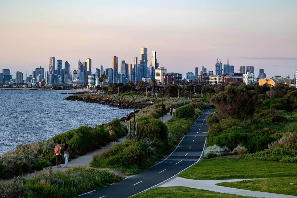 Melbourne skyline showing the city's Yarra River and a road alongside it.