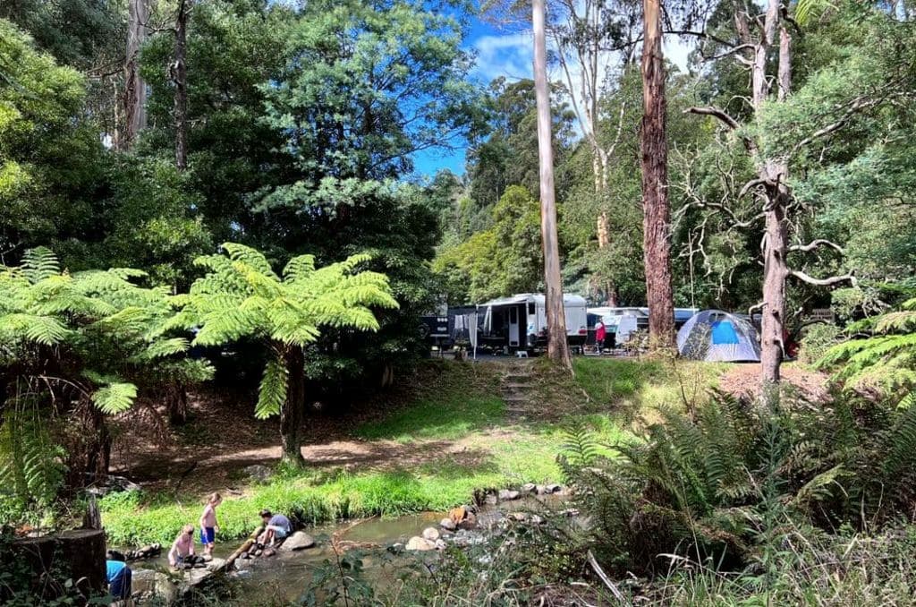 A river is seen with caravans puled up nearby.