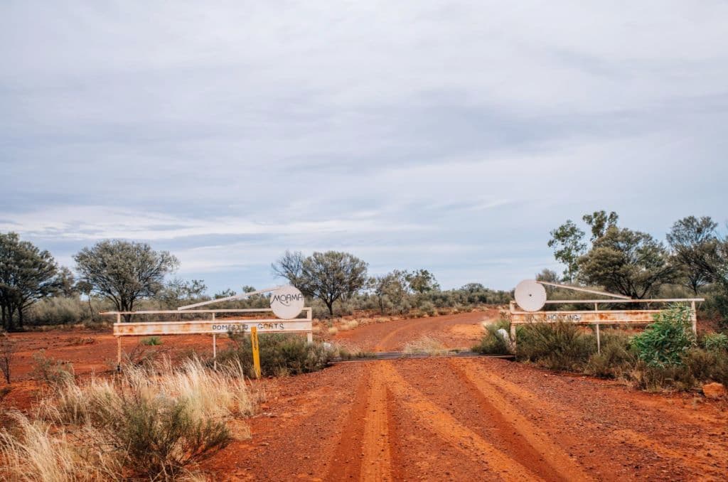A gate showing red earth and an entry sign.