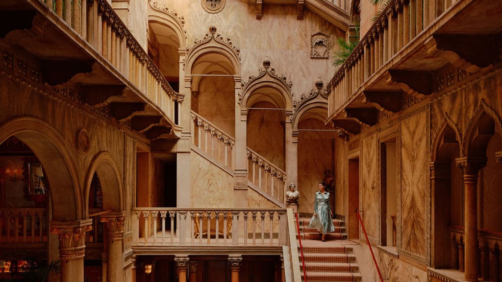 Someone walking down an elegant staircase in a luxury hotel.