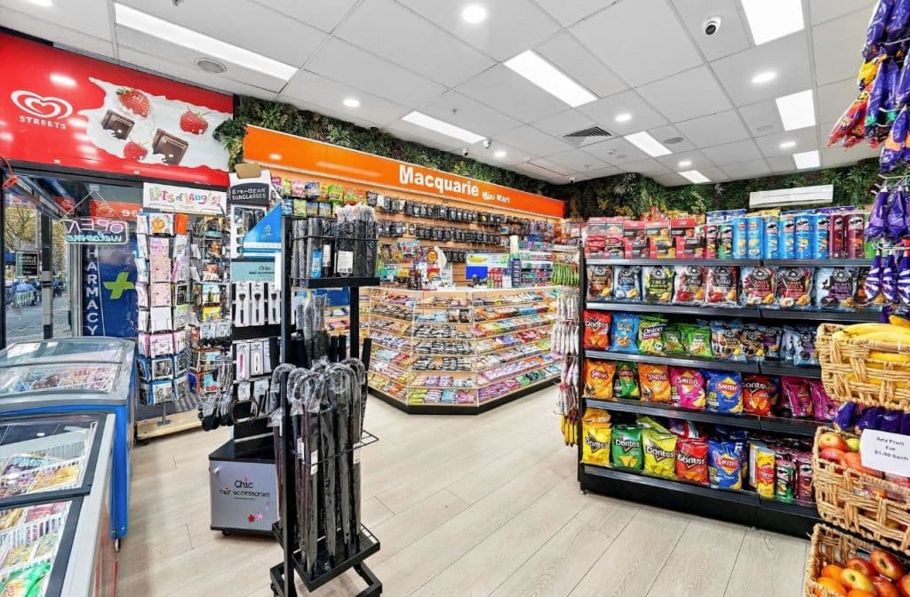 Inside the mini supermarket, wooden floors and stands with orange signage.